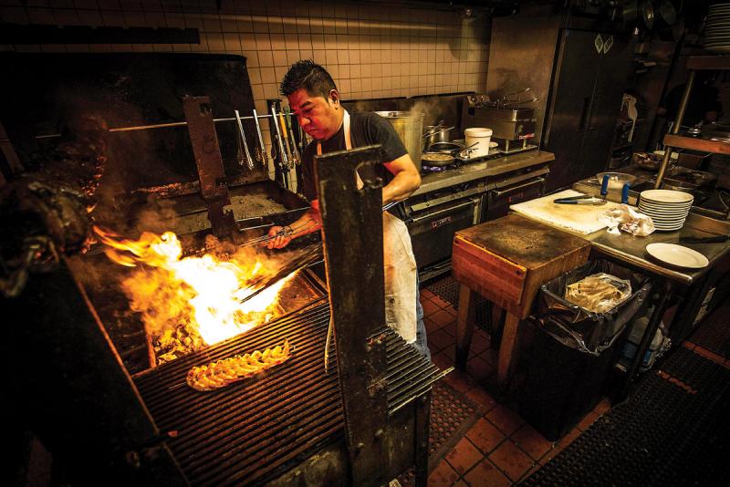 Saul, from Guerrero, Mexico, cooks over the open-pit fire in the kitchen of Zorba’s Bar & Grill on Eastern Avenue. 