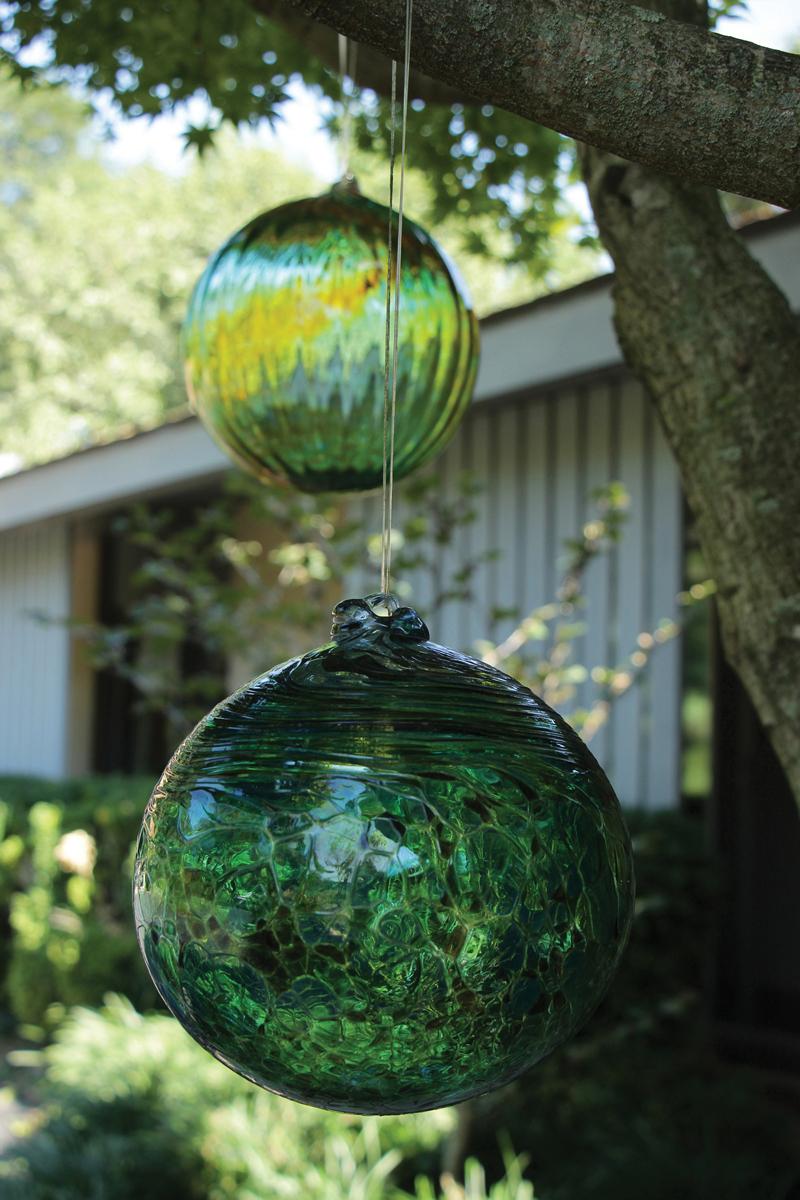 Light-catching glass balls hang from a Coral Bark Japanese maple.