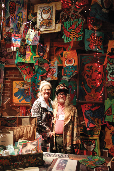 Alison Spiesman and Brian Dowdall smile in front of Dowdall's “Wall of Color” painting at Bazaart.