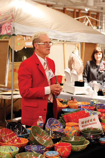 A festively dressed AVAM vendor sells his quilted holiday bags and splatter paint bowls.