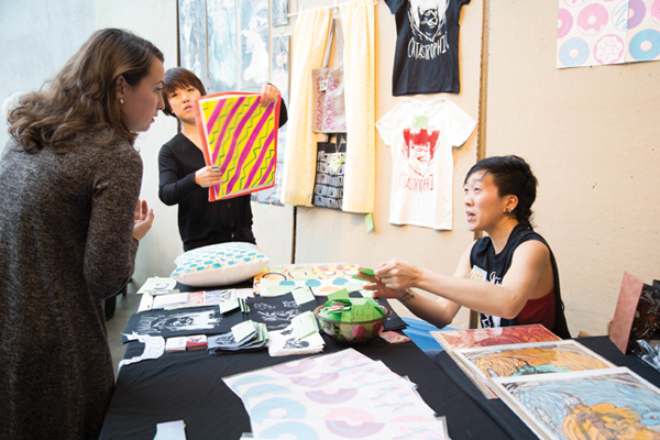 Illustrator Esie Cheng chats with a shopper about her wares and artwork at MICA’s Art Market.